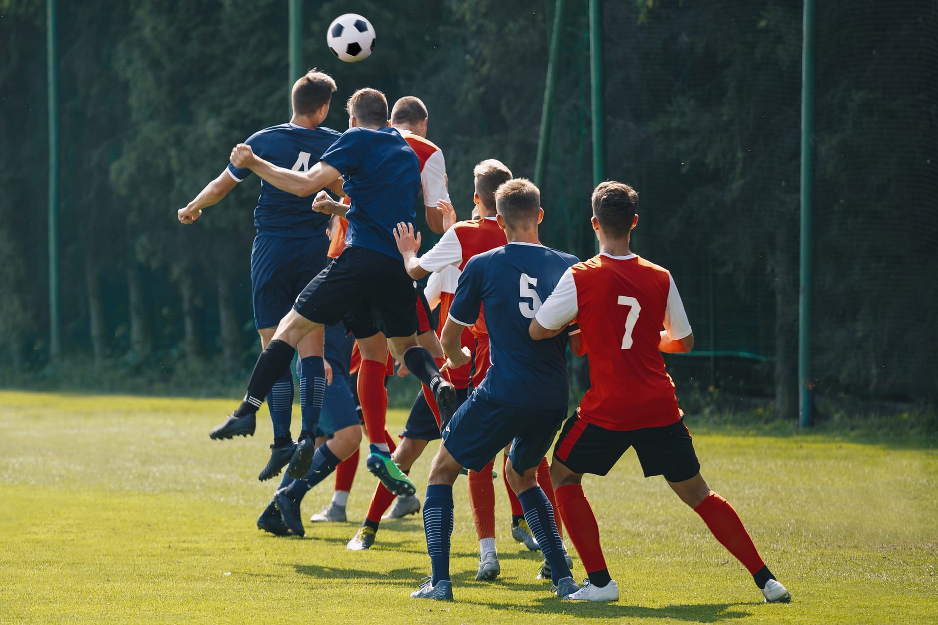 A group of football players from different teams competing to head a ball.