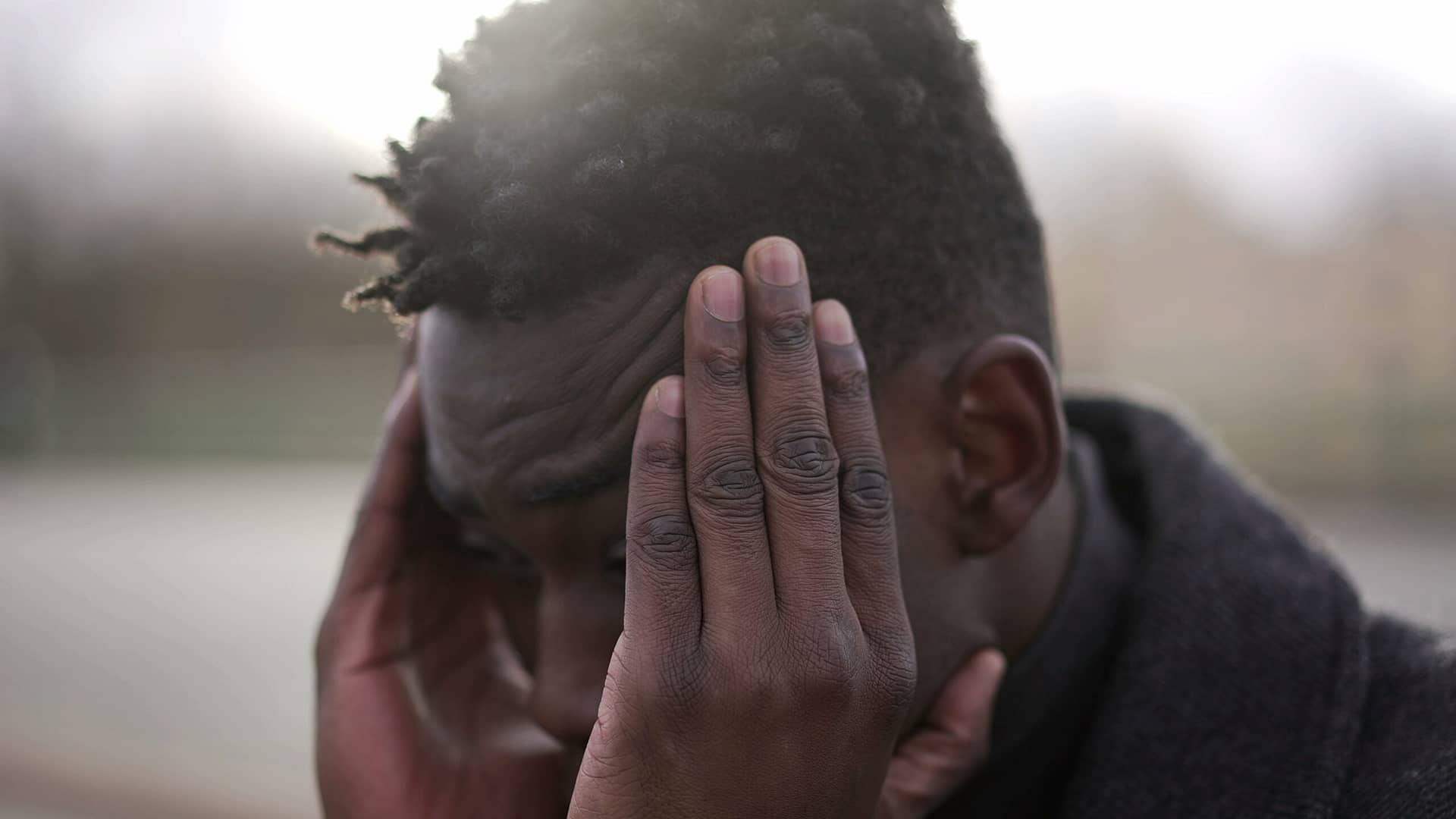 A man covering his face, showing stress or deep thought.