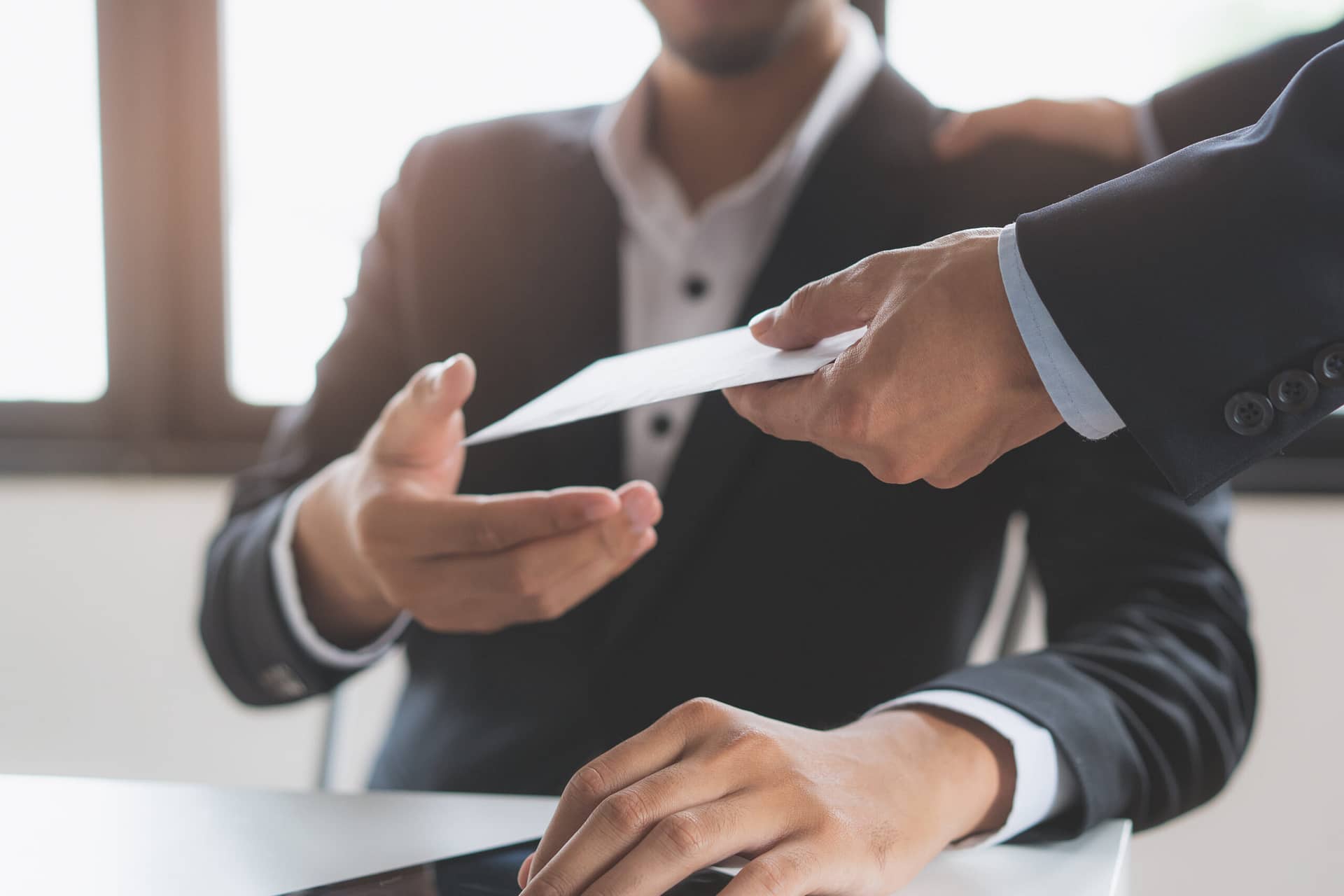 A man in an office being handed an envelope.