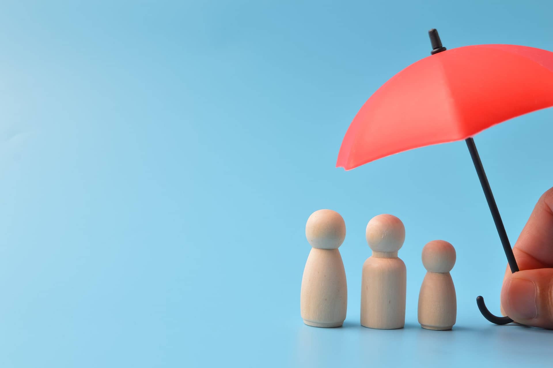 A person shields wooden figures with an umbrella.