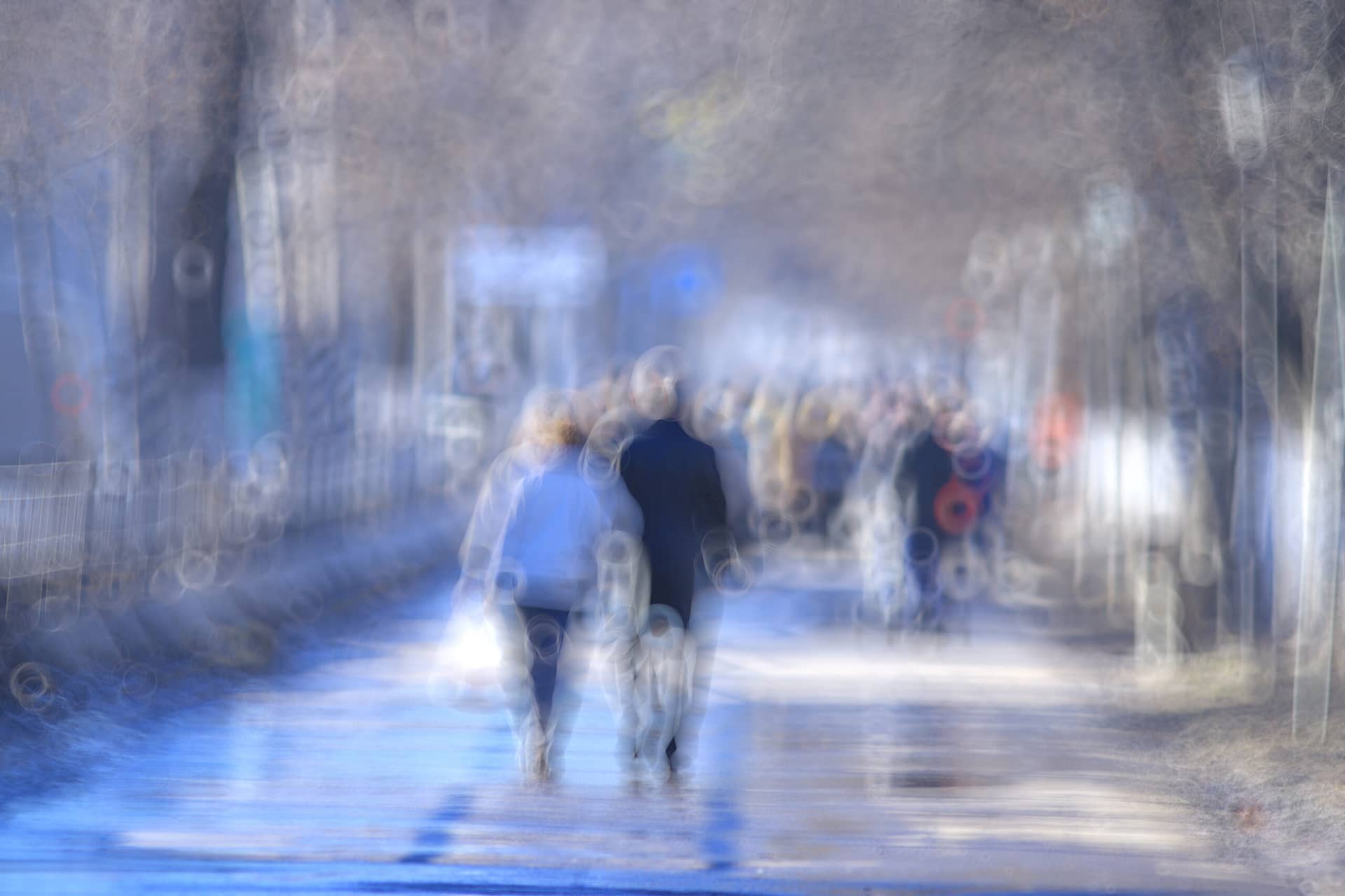 Blurry scene of individuals walking on a park path.