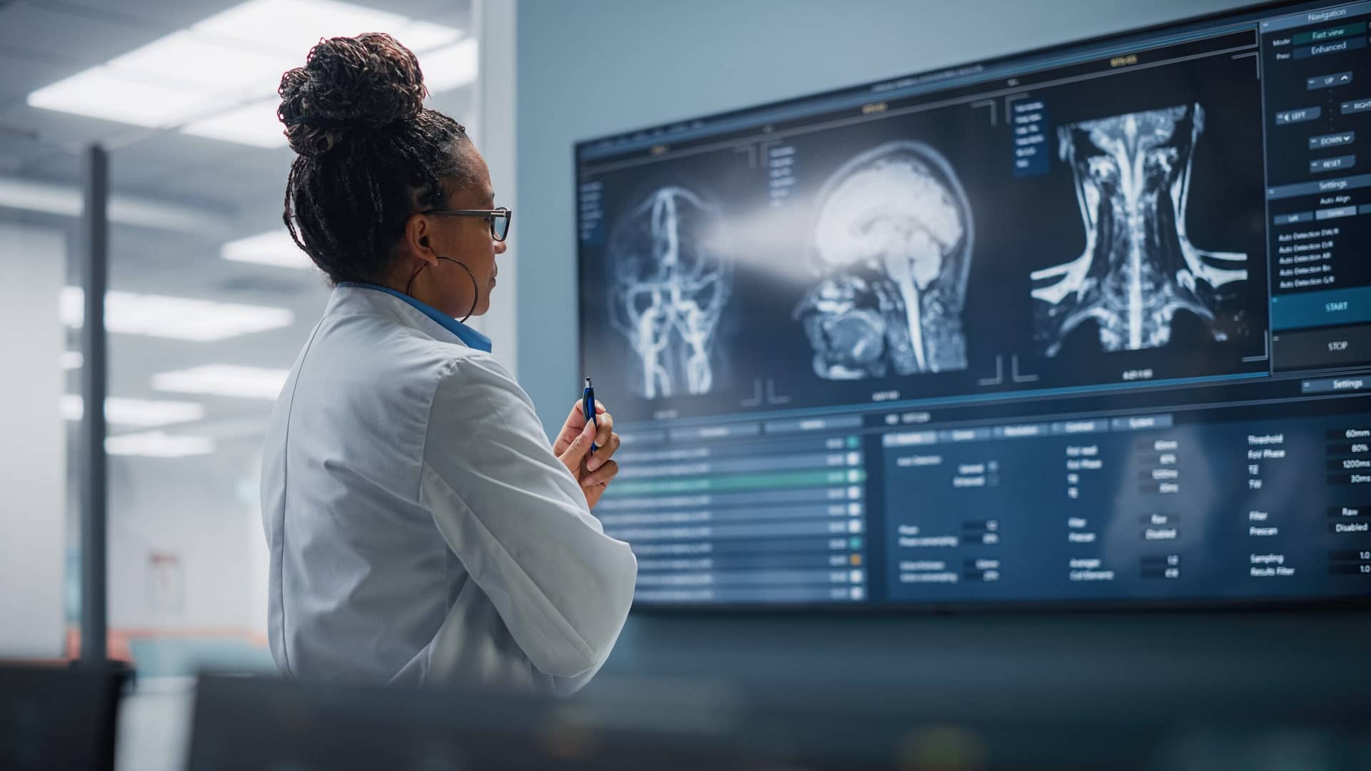 A woman in a lab coat studies a screen in a lab.