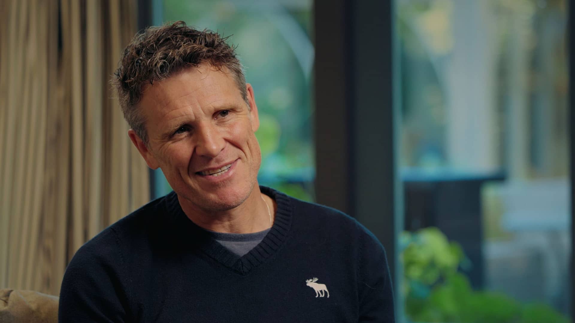 James Cracknell sits comfortably in a chair, looking relaxed and at ease.