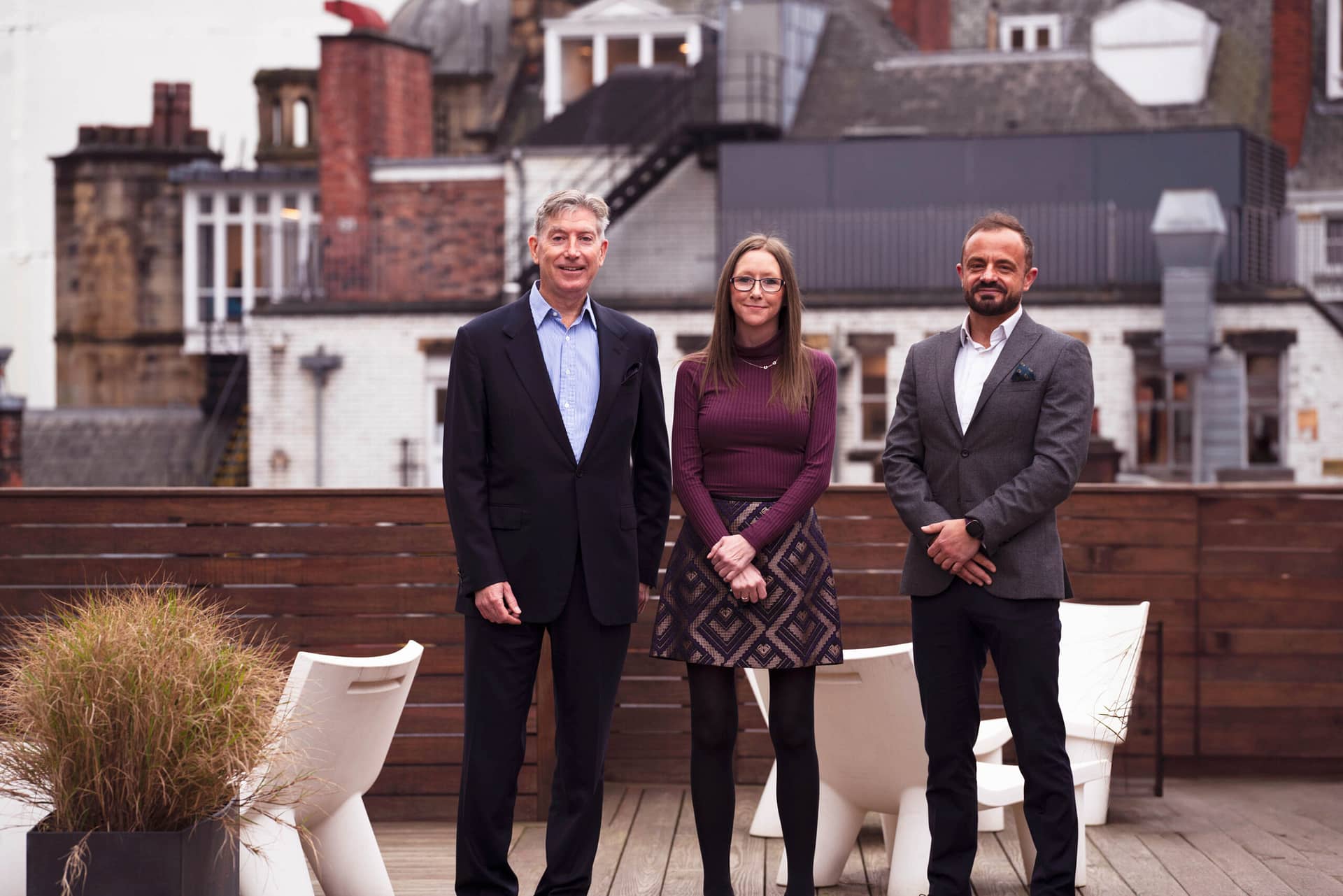 Three people gather on a wooden deck, fostering a friendly atmosphere.