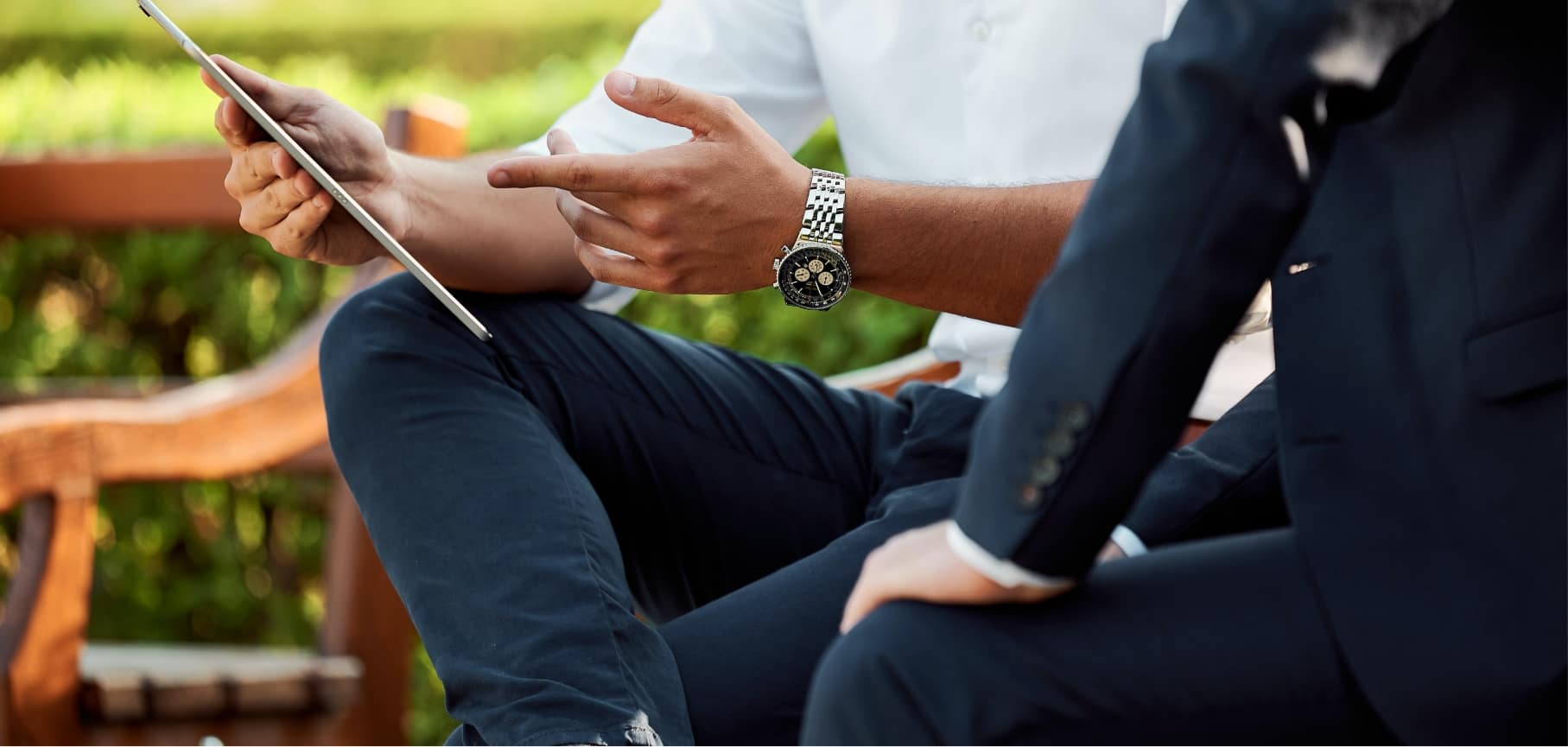 Two suited men sitting on a bench, engaging in a professional conversation