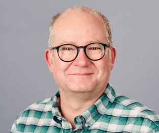 Rob is wearing glasses, and a green and white checked shirt.