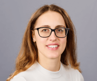 Debora is wearing black glasses and a cream jumper