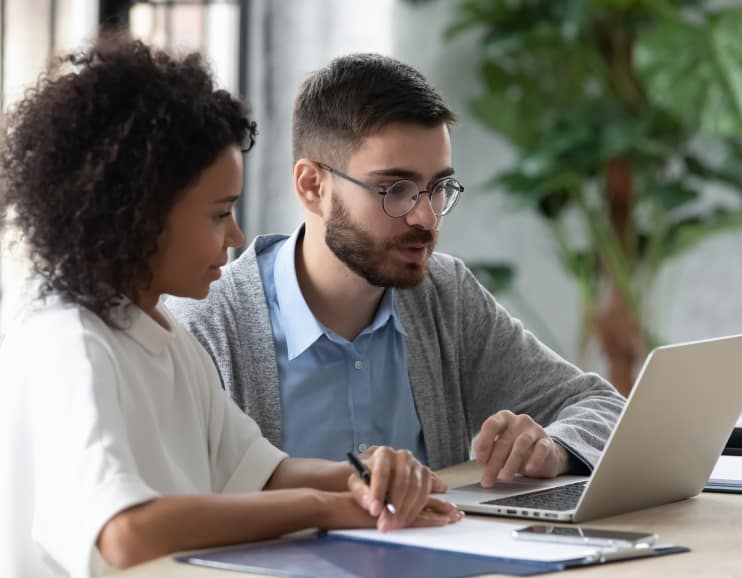 A man and woman collaborating on a laptop engaged in work