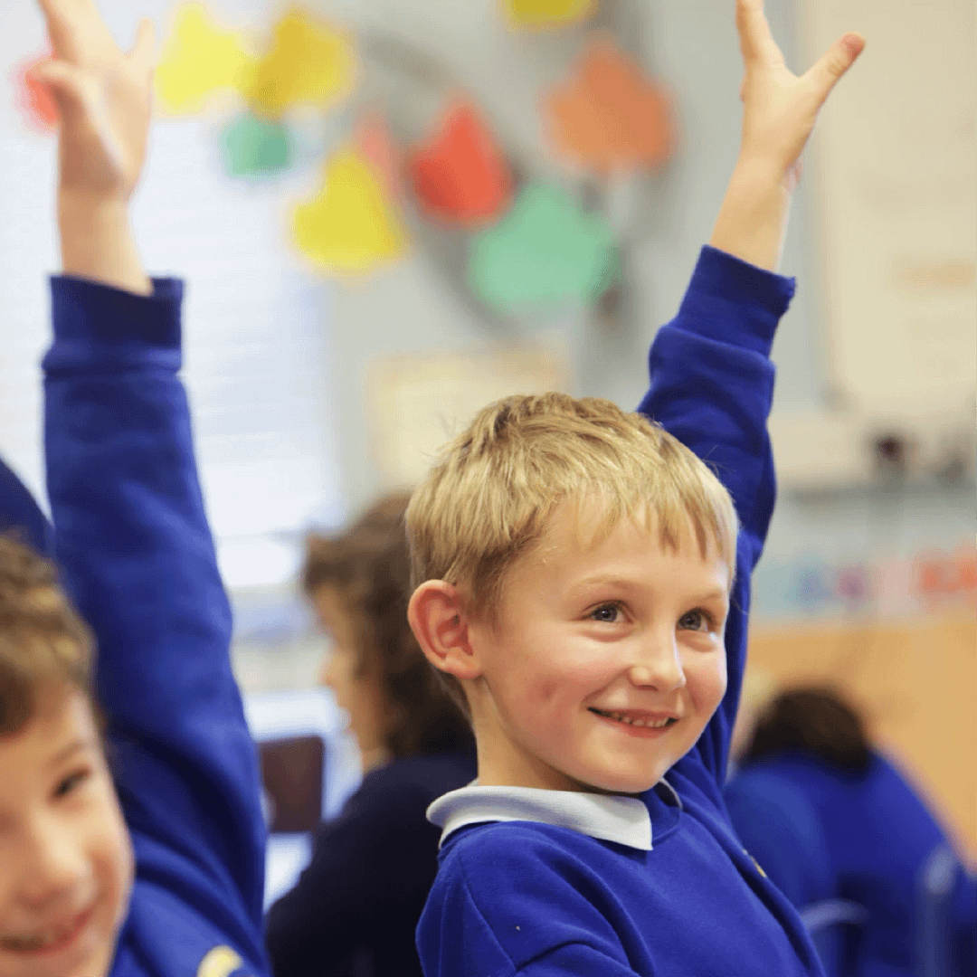 Young primary school children holding up their hands enthusiastically