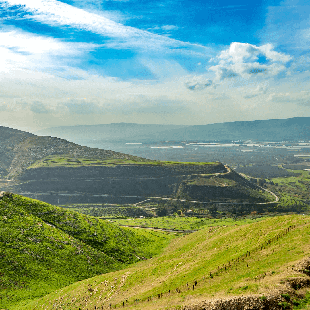 Landscape photograph of rolling green hills with a blue sky and fluffy white clouds