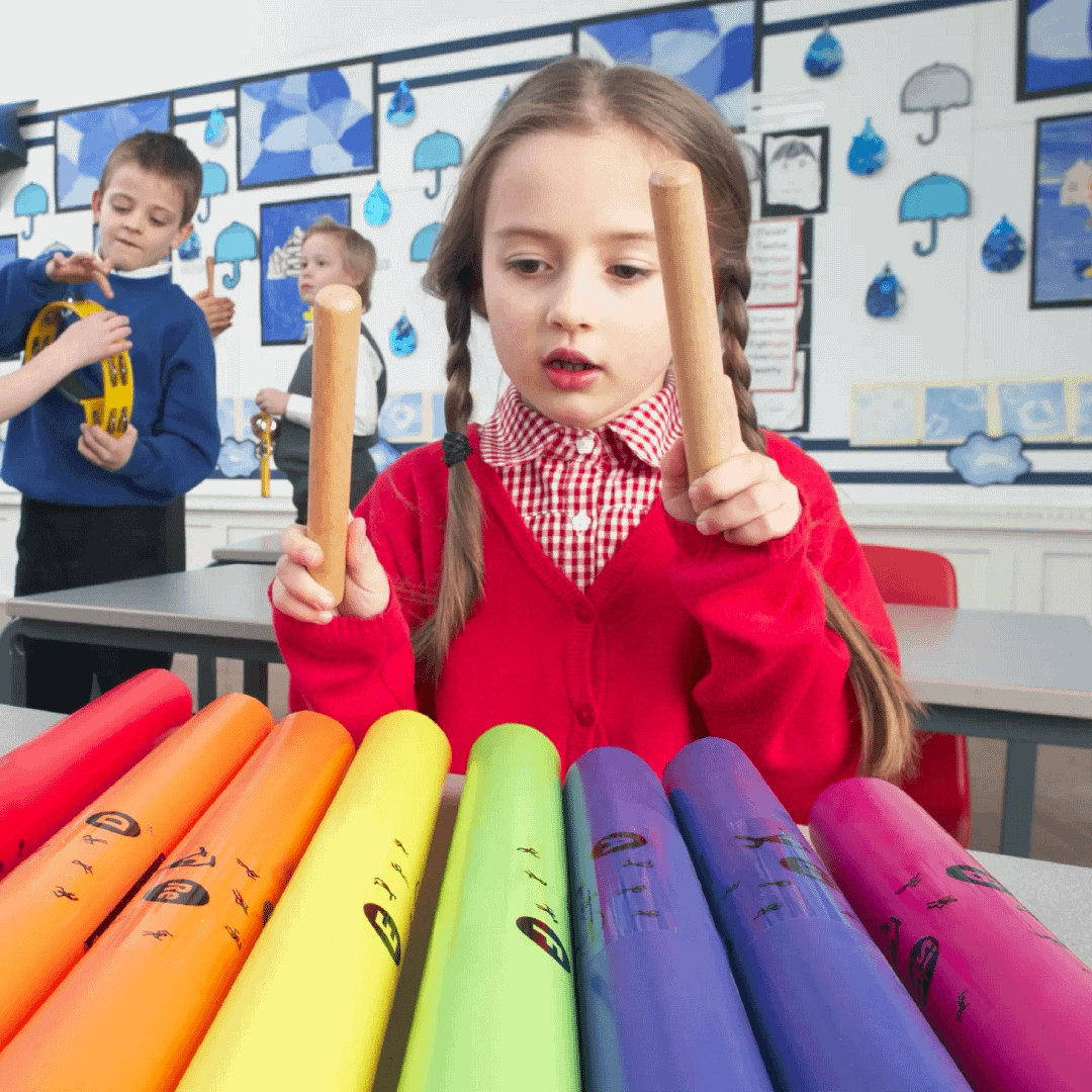 A young primary school girl wearing uniform playing boomwhacker tuned percussion tubes