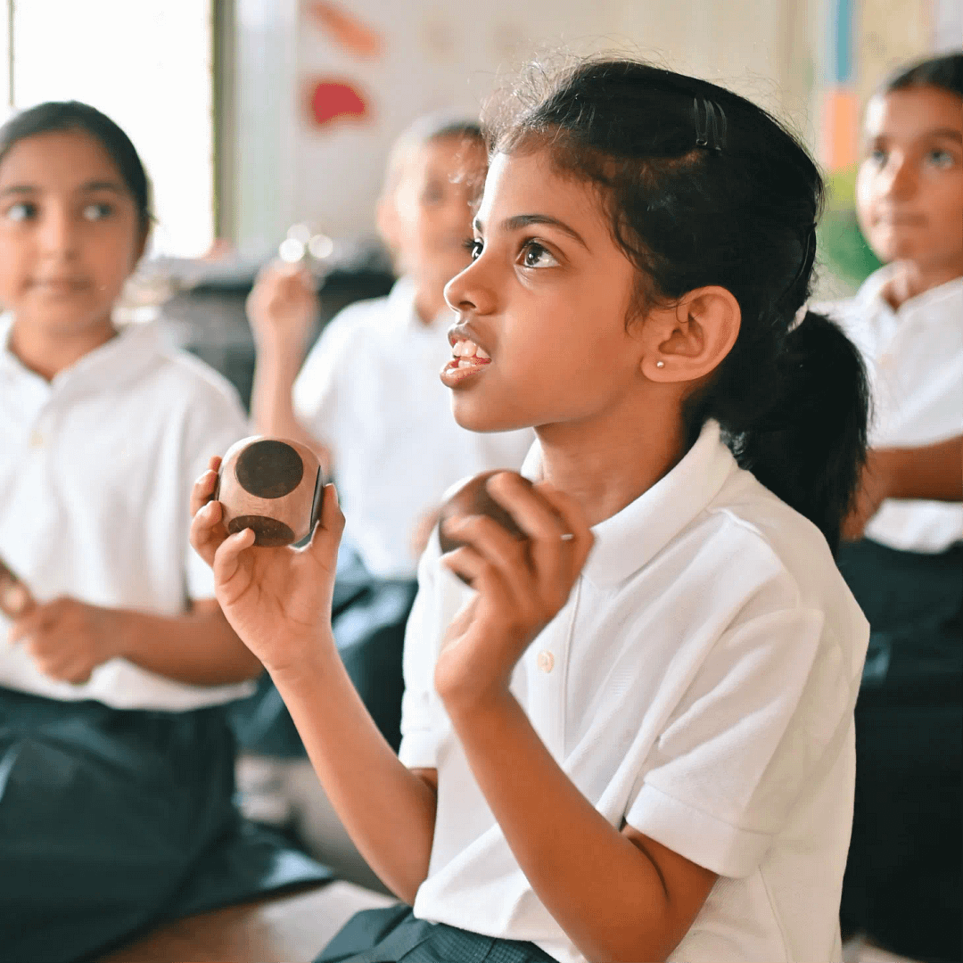 A young girl holding wooden blocks ready to tap a rhythm