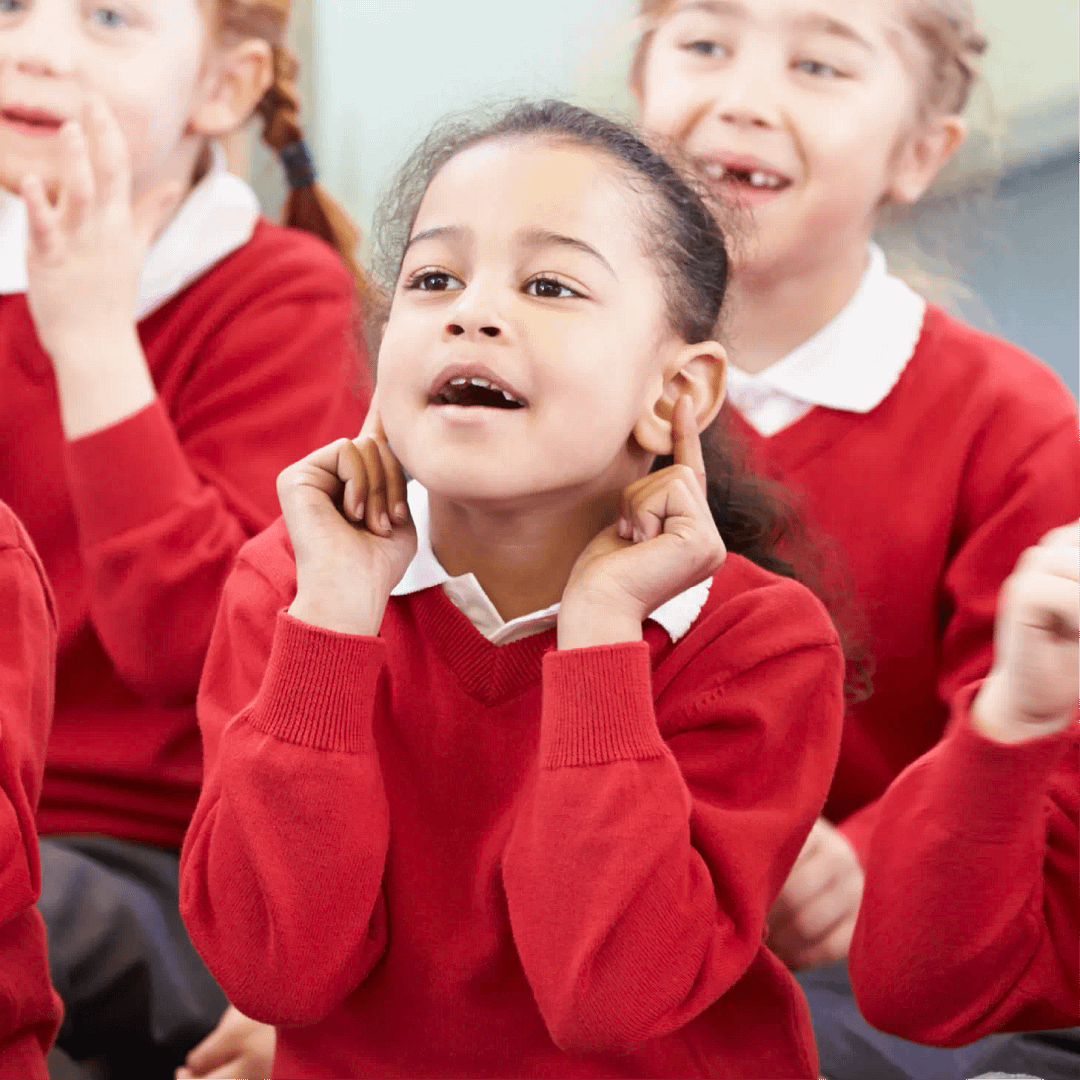 A group of young children in red school uniforms participating in a classroom activity