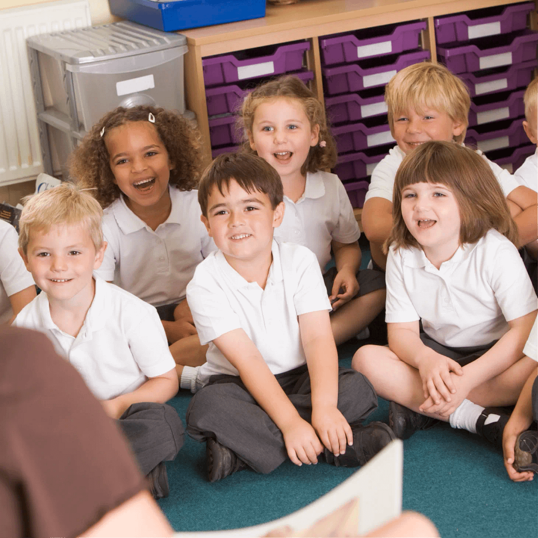 A group of primary school children sitting and smiling during a classroom activity