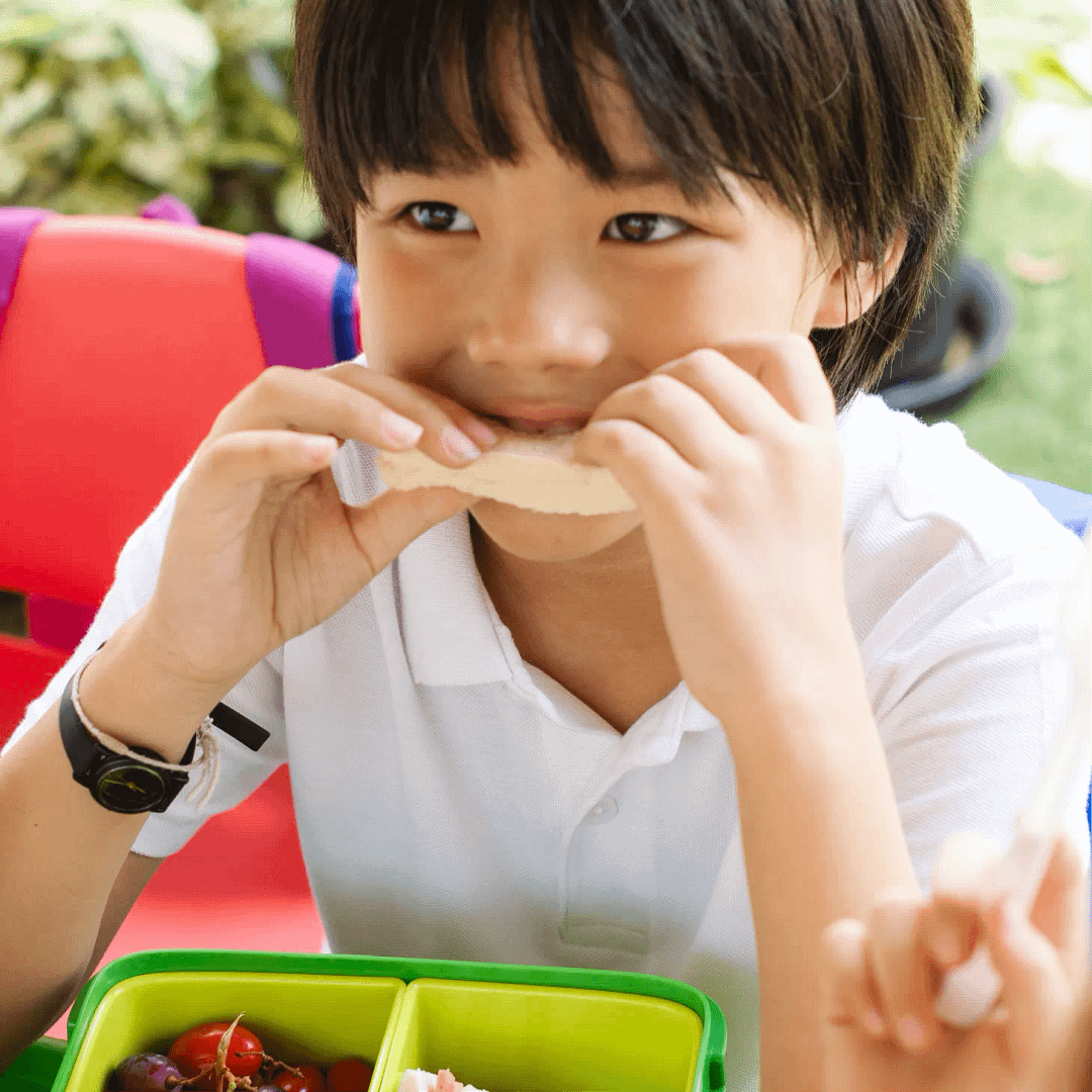 A pupil eating lunch outdoors at school
