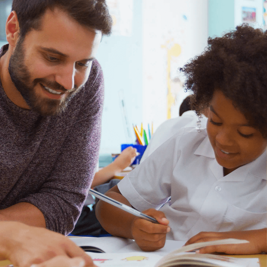A teacher helping a pupil with their classwork at a desk
