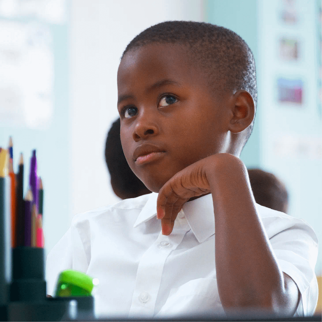 A young child in a white shirt listening attentively during a class.