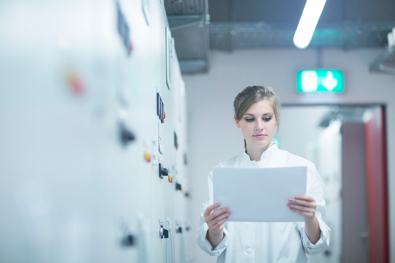 Young female scientist reading paperwork in technical room
