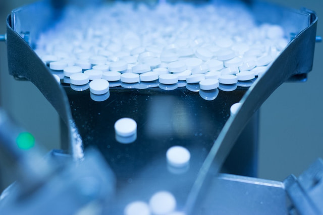 White pills filtering through a manufacturing process