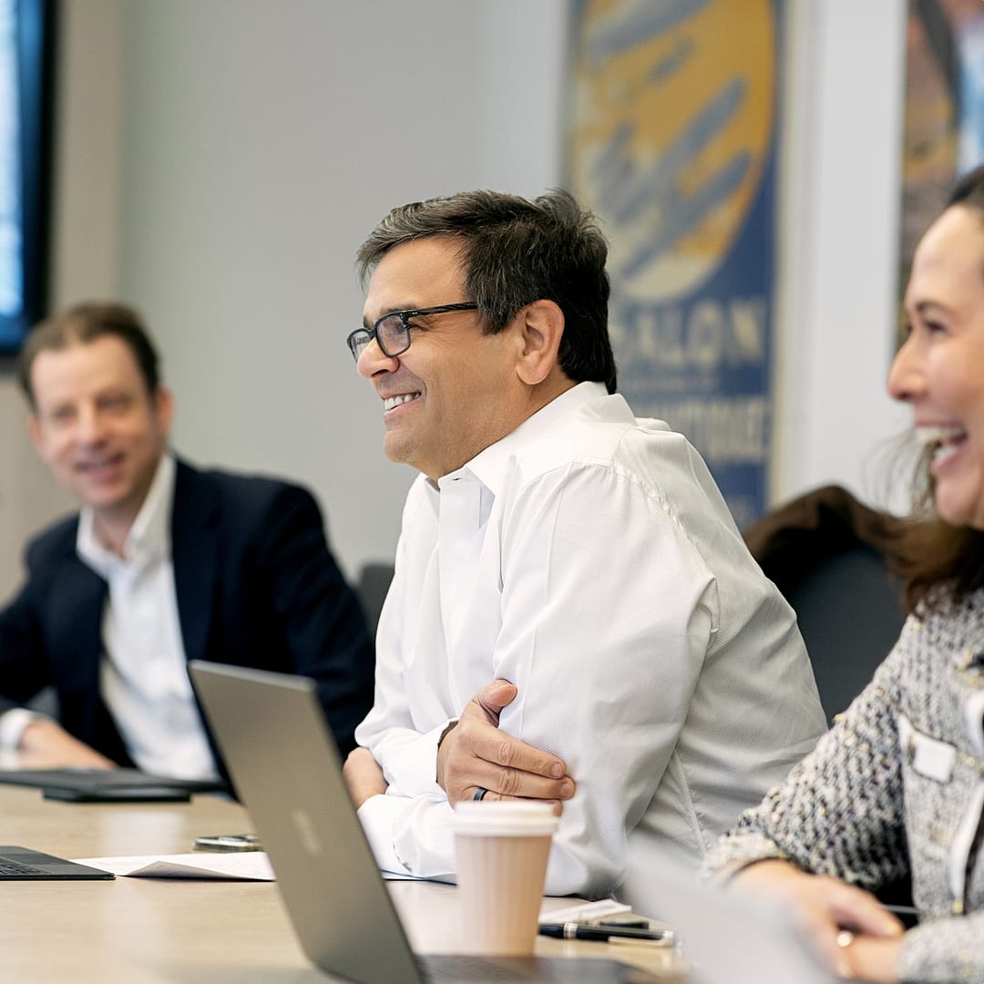 Smiling Jeremy Coller at a table with colleagues.