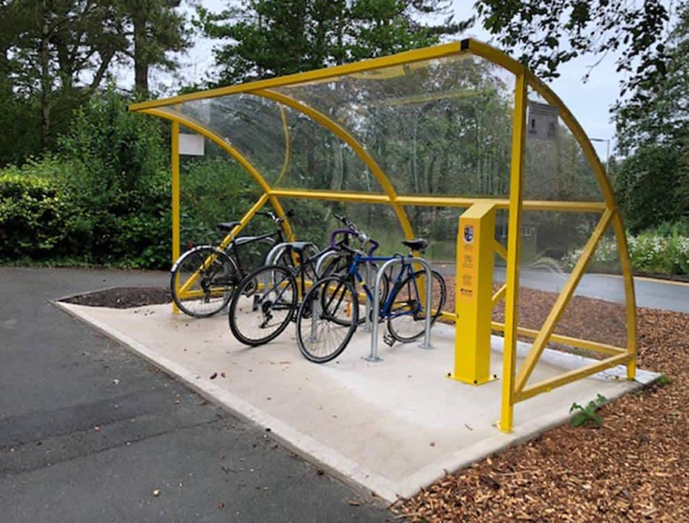 Glass curved bike shelter with electric stations and floor mounts