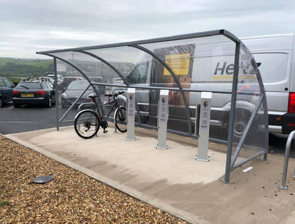 Glass curved bike shelter with electric stations and floor mounts