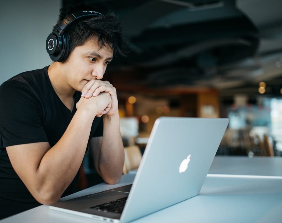 Man sat at a laptop focusing on work with headphones